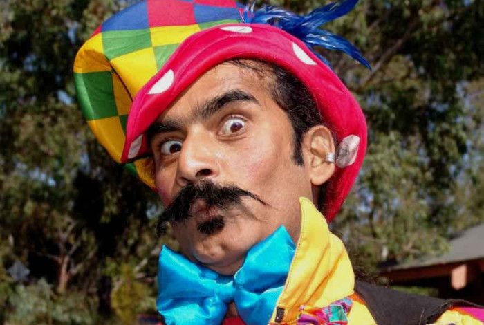 Man dressed as jester staring into the camera. 