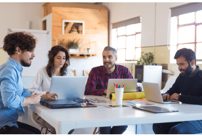workers sitting at computers having a meeting