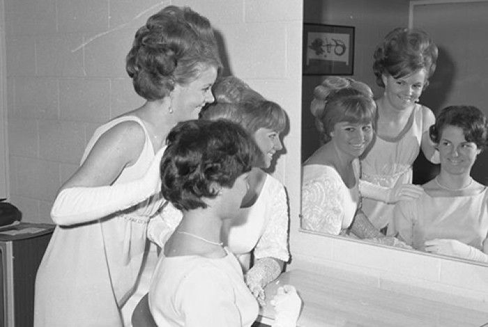 Black and white image of three girls looking in the mirror