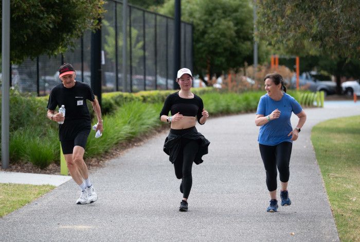 A man and two women are running in a track at Dandenong Park