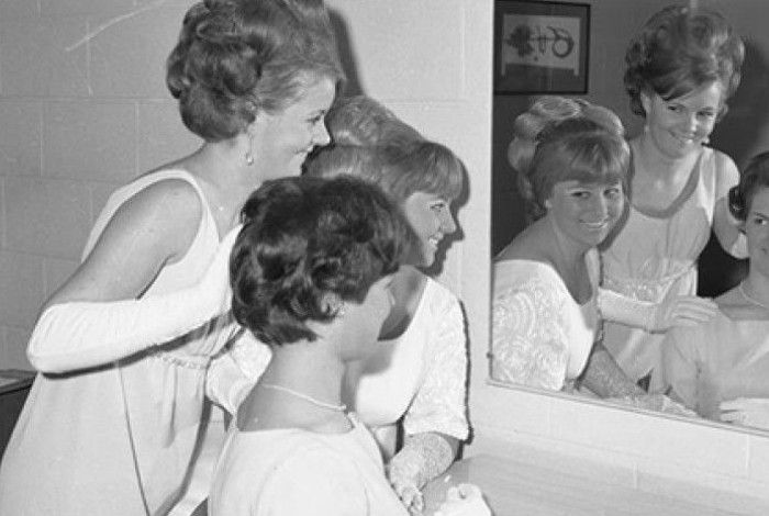 Three women looking in a mirror