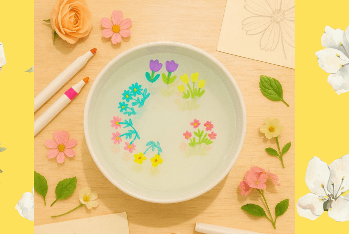 Ink flower illustrations floating in a bowl of water.