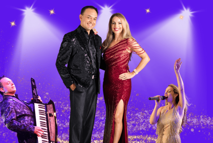 A couple stand against a purple background with a spot lights shining down