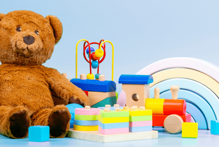 Teddy bear and various toys against a light blue background