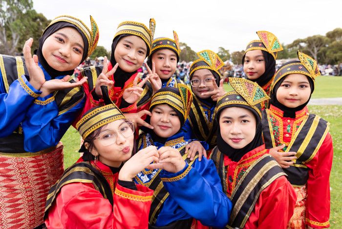 A group of smiling children wearing traditional Indonesian clothing