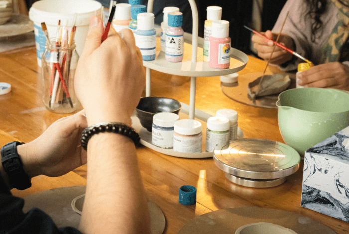 People painting ceramics on a table with painting supplies. 