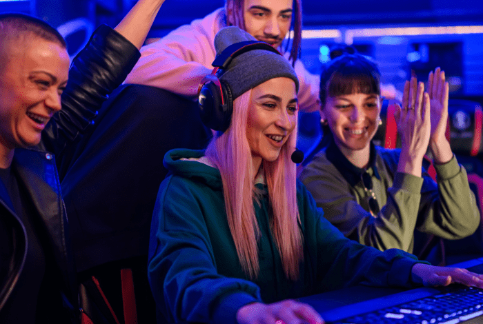 Several people wearing headsets and enjoying live gaming at computer station. 