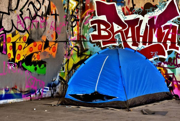 A tent with graffiti on the wall behind