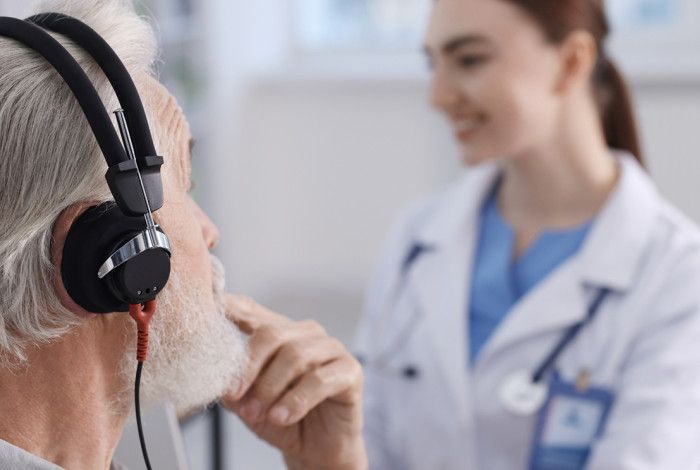 A healthcare professional testing a patient's ear in a medical office.
