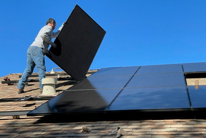 A man installing solar panels on the roof of a house