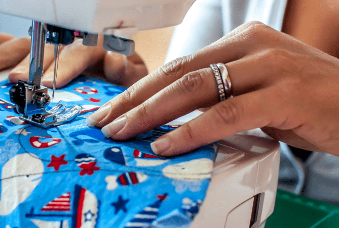 Closeup of person using sewing machine on piece of fabric.