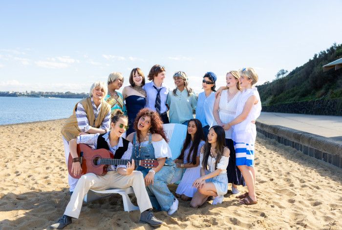 People huddled together singing on a beach.