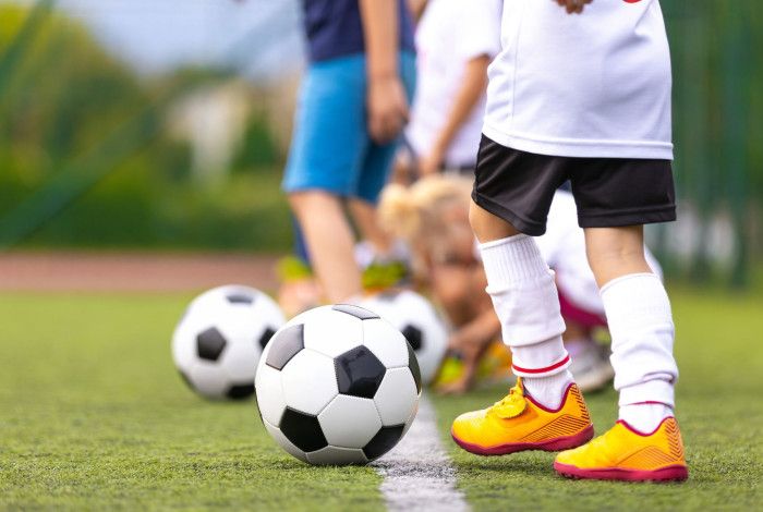 A number of children playing soccer, the picture only shows their legs and soccer balls.
