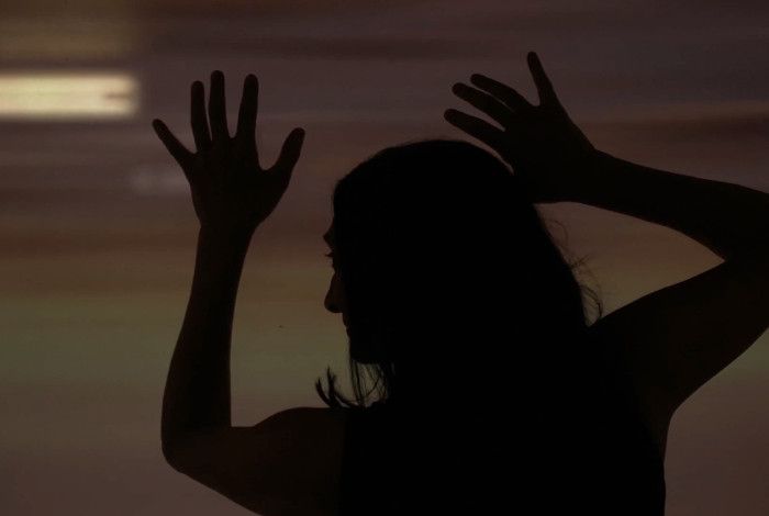 Silhouette of a lady with her arms up in the air 