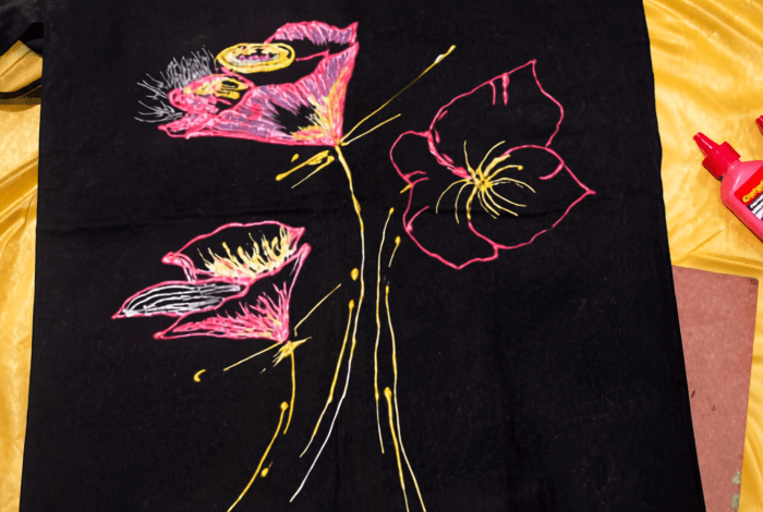 A colourful image depicting three flowers painted on black fabric.
