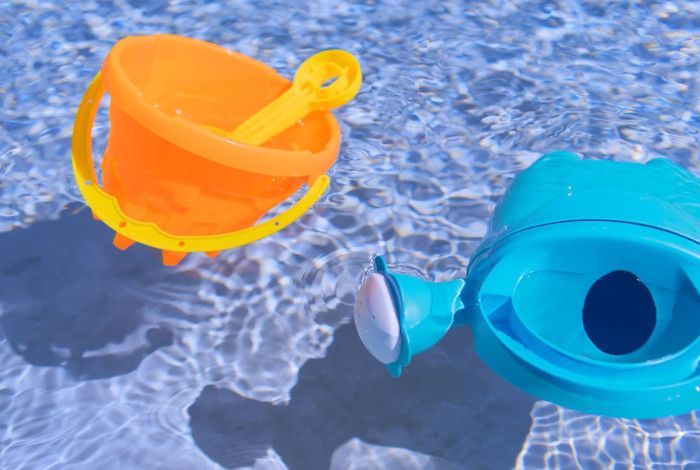 Bucket, spade and watering can floating in a pool