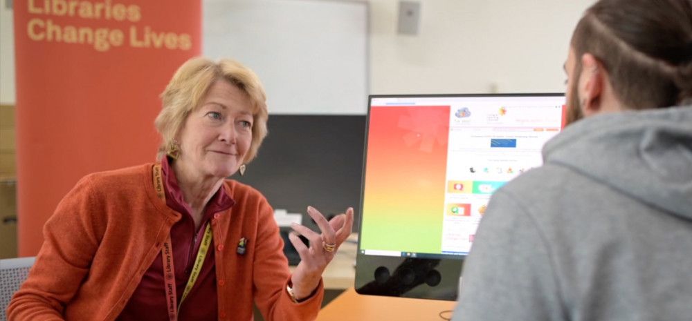 Teacher talking to a young man working at the computer