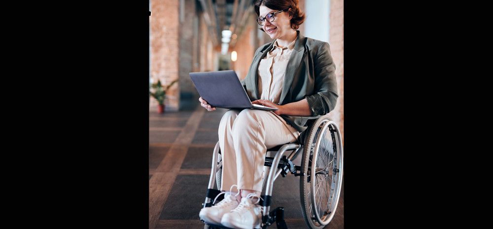 photo of woman sitting in wheelchair while using laptop