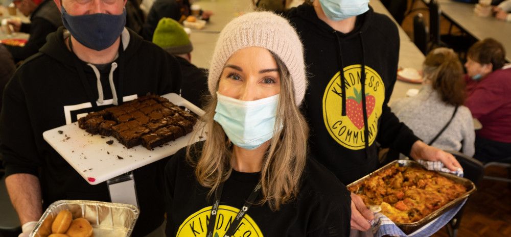 Volunteers from Kindness Community holding plates of food