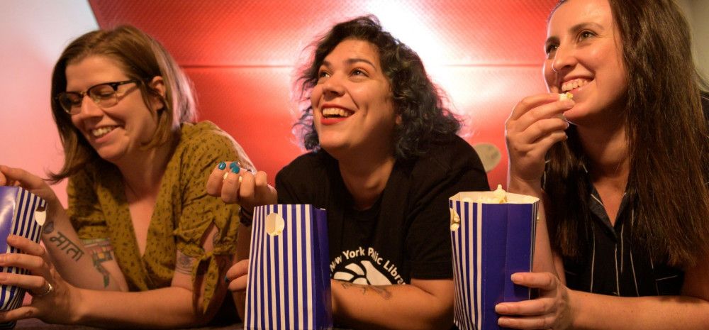 Image: Three women eating popcorn and watching a film