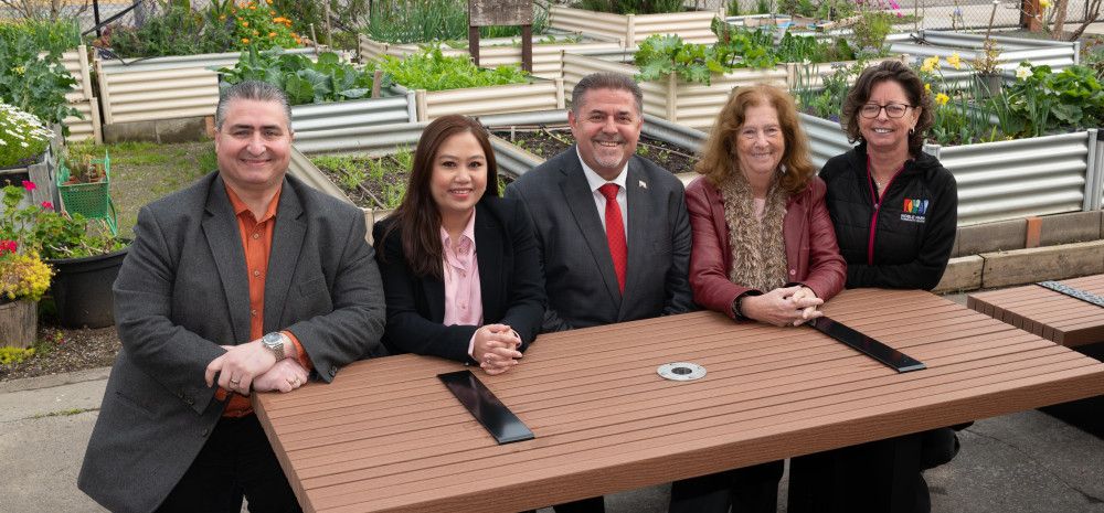 A group of people sitting at a new outdoor table at Noble Park Community Centre