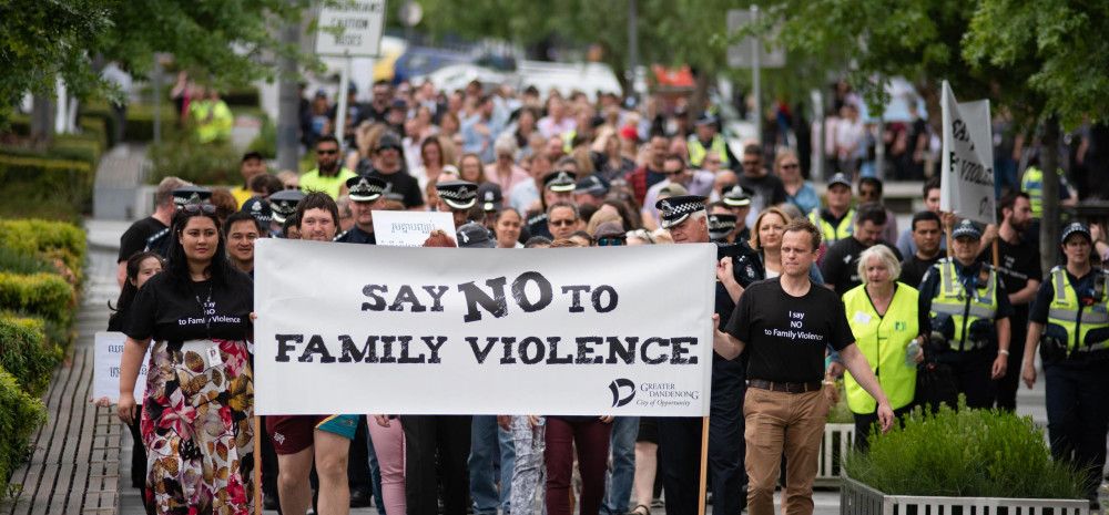 people walking holding baber saying say no to family violence