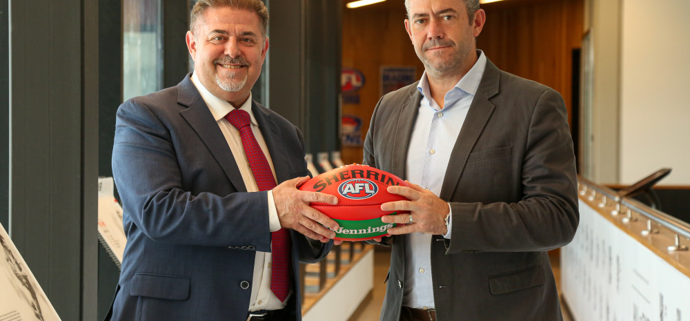Mayor Cr Jim Memeti shaking hands with St Kilda Football Club Chief Operating Officer Simon Lethlean while holding a football