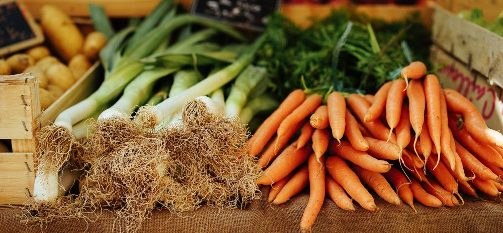 Fresh produce including carrots and leeks layed out on a table