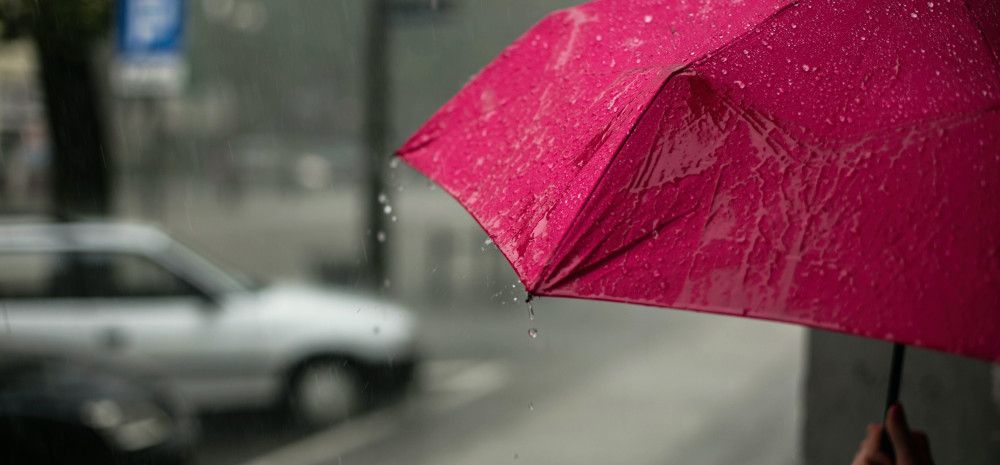 A red umbrella getting rained on.