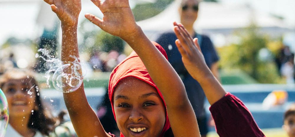 A smiling girl popping bubbles with her hands