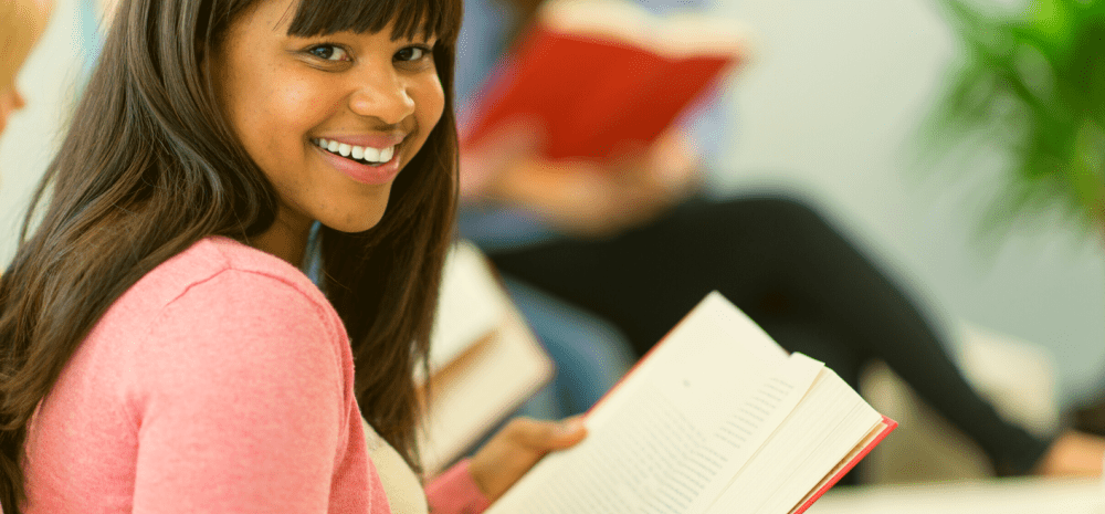 A person reading a book and smiling at the camera