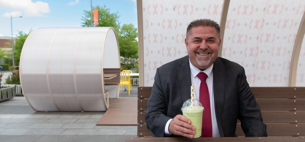 Councillor Jim Memeti enjoying a juice while sitting inside an outdoor dining pod