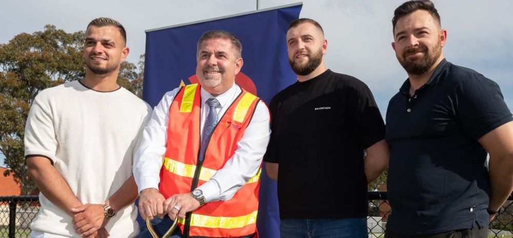 Four men standing together while one leans on a shovel.