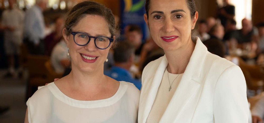 Two women dressed in white standing close together.