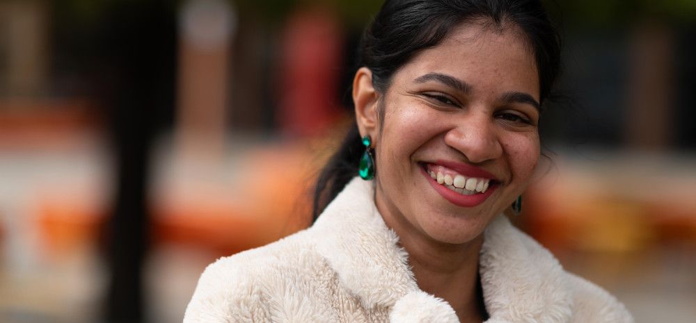 Young woman in a fluffy white coat smiling at the camera.