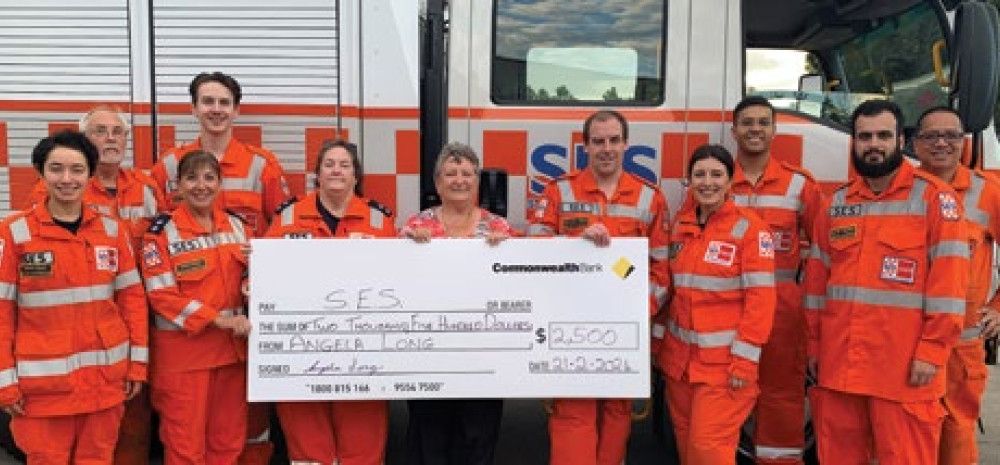 Angela long standing with SES volunteers holding a giant cheque