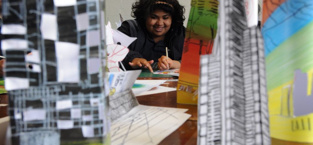 A person behind some sculptures on a table.