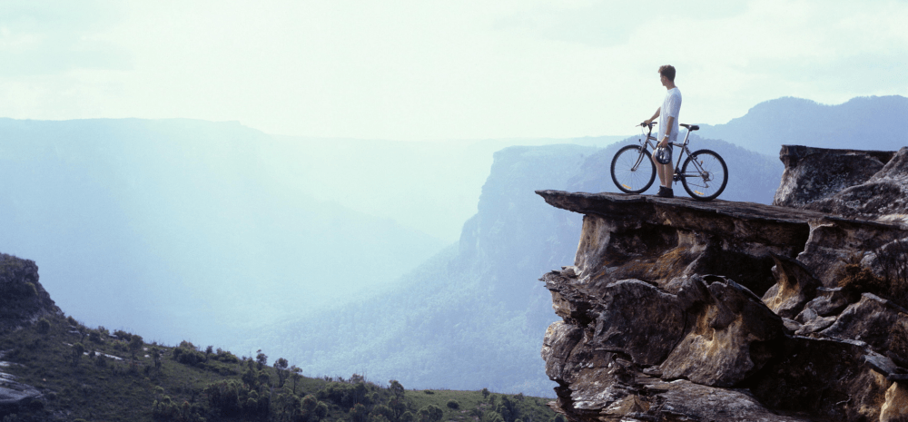 A person and a bicycle on a mountain.