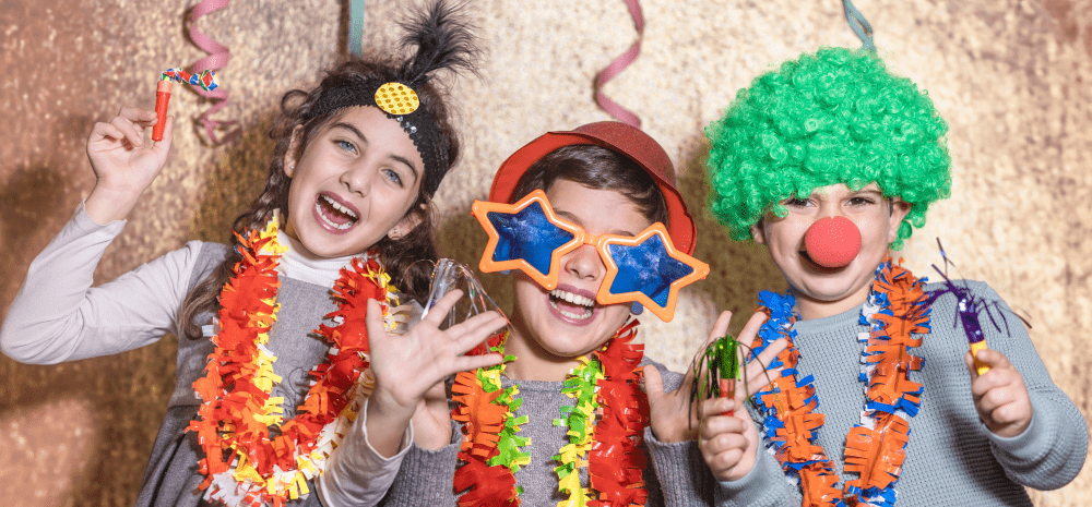Three children dressed up in colourful costumes. They are smiling.