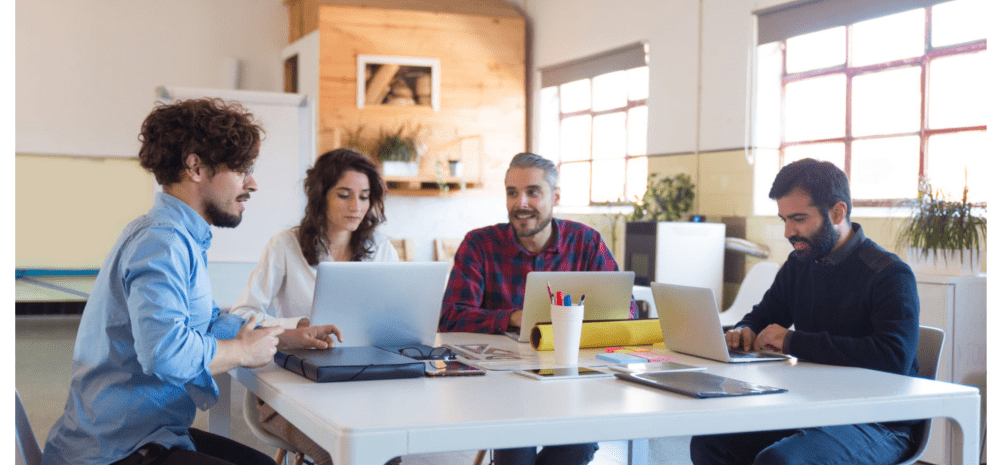 workers sitting at computers having a meeting