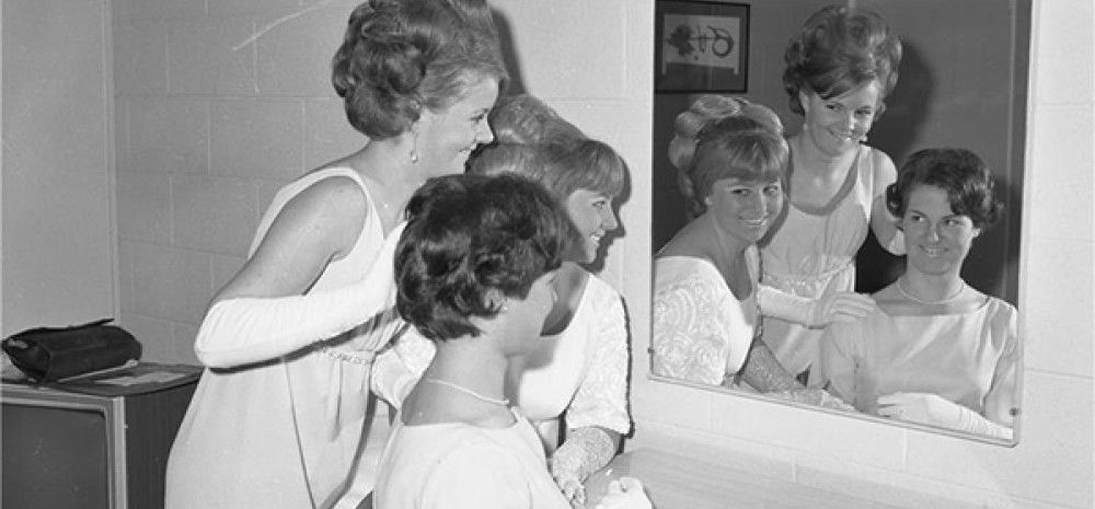 Black and white image of three girls looking in the mirror