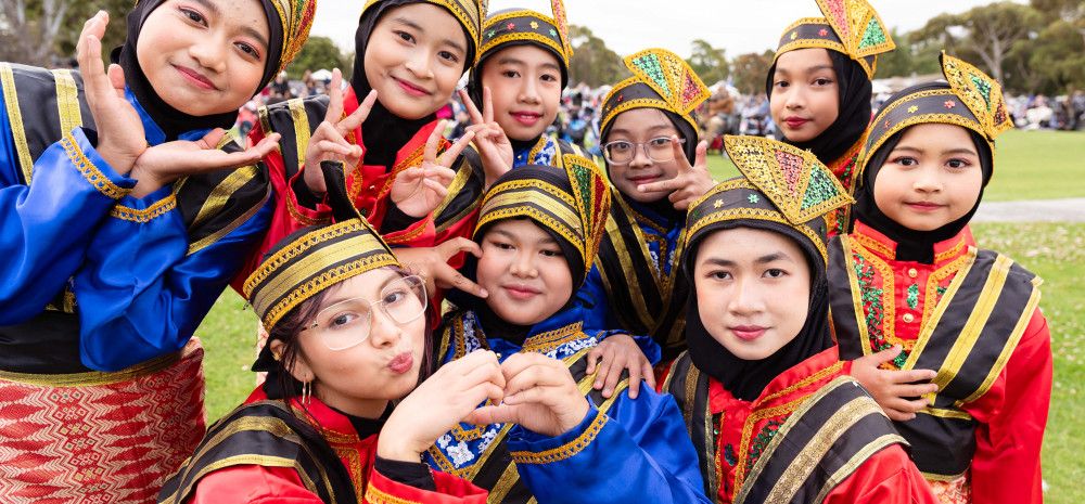 A group of smiling children wearing traditional Indonesian clothing