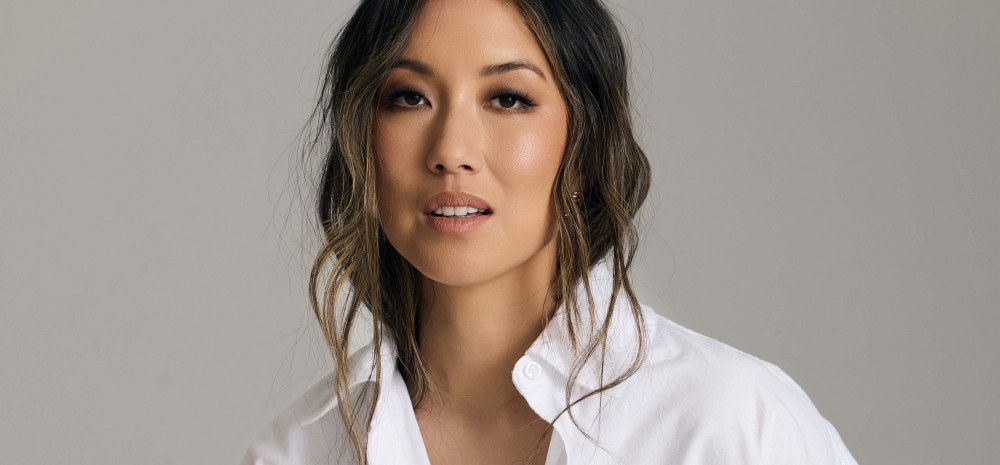 A smiling woman posing in a white shirt and black pants