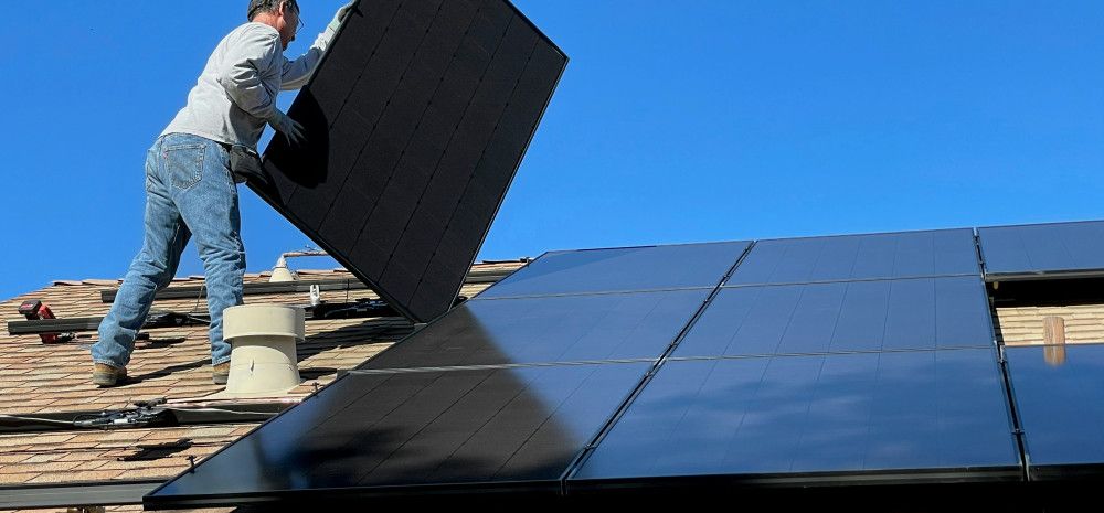 A man installing solar panels on the roof of a house
