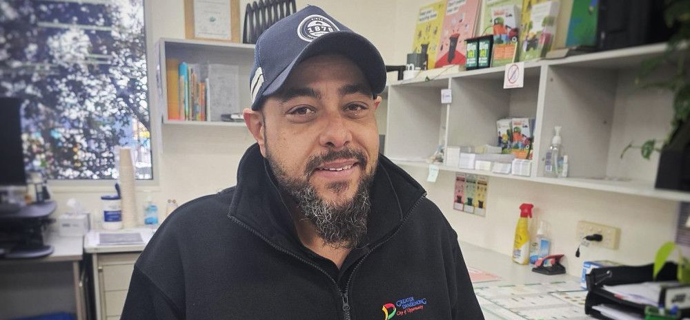 A smiling man in a cap and a dark jumper.