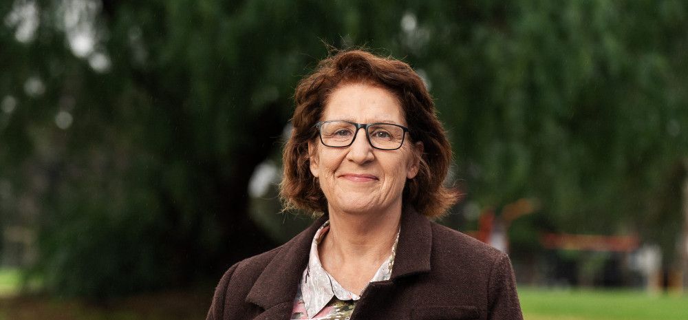 A smiling woman stands in a park.