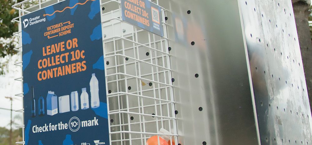 A small cage attached to the side of a stainless steel rubbish bin with a sign that reads “Leave or collect 10 cent containers”.