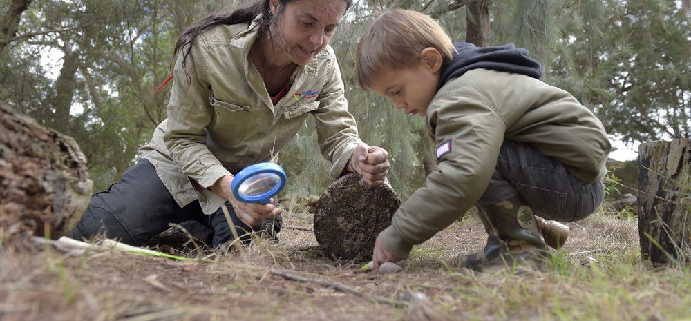 A woman and a young boy crouch down and are playing on the ground together