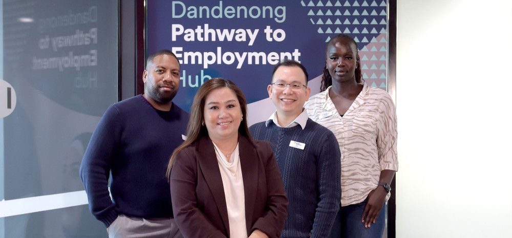Four smiling people pose in front of a shop front with a sign that reads Dandenong Pathway to Employment Hub