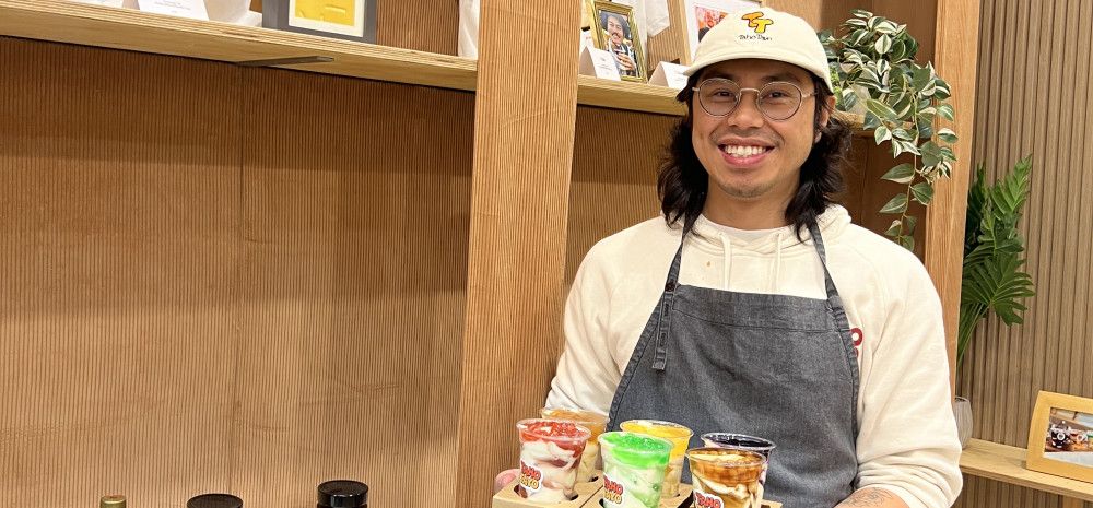 A smiling man holds a tray of sweet treats
